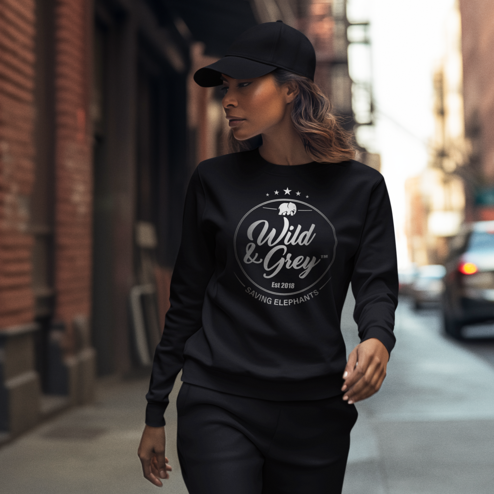 Woman wearing a black sweatshirt with 'Wild & Grey' logo on a city street.